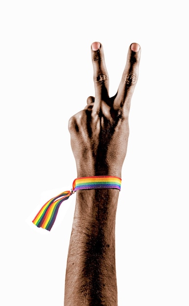 Mano negra con una pulsera con los colores de la bandera LGBT mostrando dos dedos