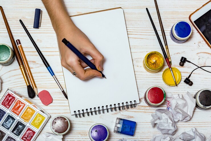 Foto la mano de la niña artista y las páginas del álbum, pinturas, lápices, óleo, pincel sobre un fondo de madera