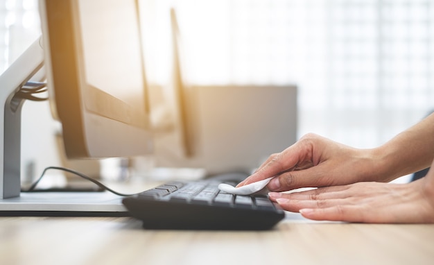 La mano de la niña está limpiando el teclado de la computadora Para limpiar bacterias y virus Coronavirus