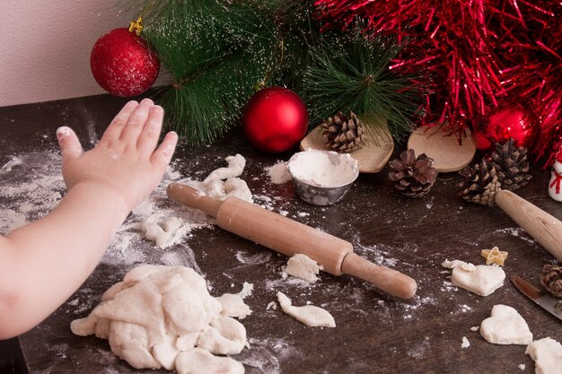 La mano de la niña hace galletas de Navidad, fondo de Navidad, colores brillantes, adornos de árbol de Navidad rojo, espacio de copia