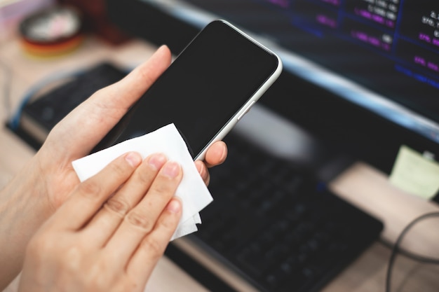 Mano de la niña limpiando el teléfono móvil.