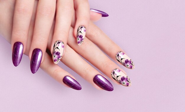 Mano de la niña. manicura morada. uñas acrilicas largas de colores.  manicura femenina y motivos florales. | Foto Premium