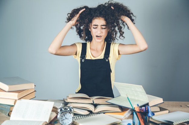 Mano de niña en el pelo con libros sobre el escritorio