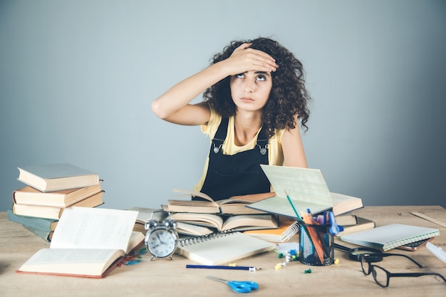 Mano de niña en el pelo con libros sobre el escritorio