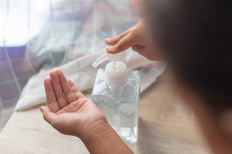 mano de niña pequeña que usa un dispensador de gel desinfectante para lavado de manos, contra el nuevo coronavirus o la enfermedad del virus Corona (Covid-19) en interiores públicos