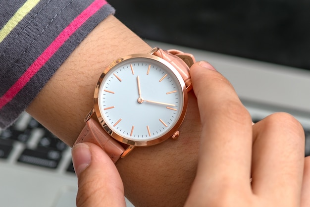 La mano de la niña con reloj de pulsera frente a una computadora portátil