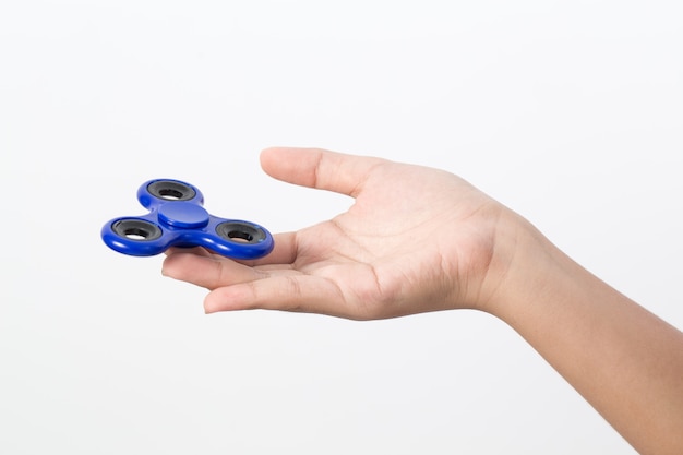 Mano de niña sosteniendo el juguete popular fidget spinner en blanco