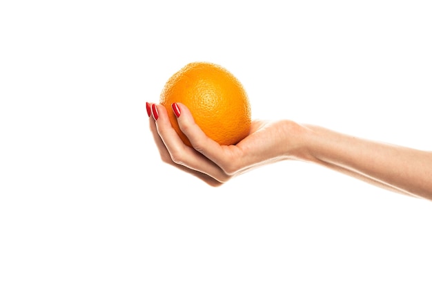 La mano de la niña sostiene una rodaja redonda cortada de naranja tropical fresca Una naranja en la mano de una mujer sobre un fondo blanco está aislada Rodaja de naranja La niña sostiene suavemente un cítrico en la mano