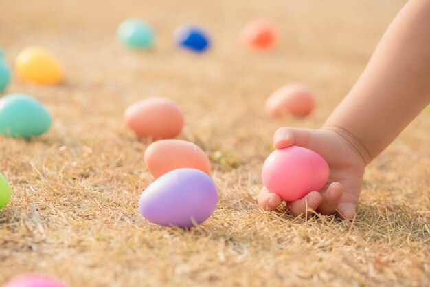 Foto la mano del niño busca huevos de pascua en los rayos del sol poniente.