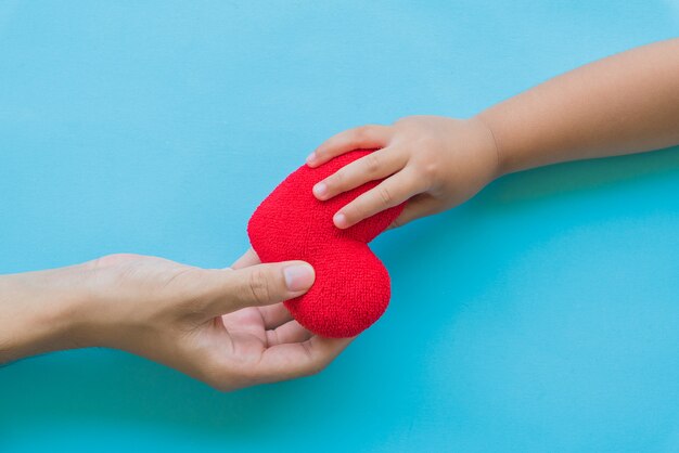 Mano de niño dando corazón rojo a su padre, relaciones familiares felices