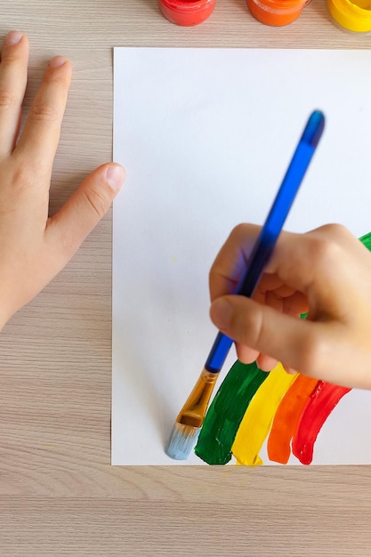 Foto la mano del niño dibuja un arco iris sobre un fondo blanco.