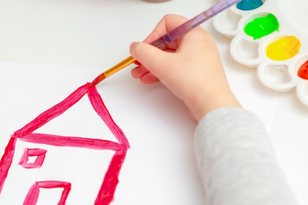 La mano del niño dibujando la casa.