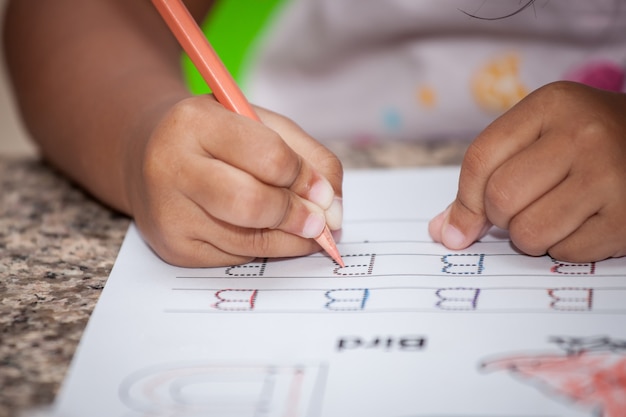 Foto mano de niño escribiendo su tarea con lápiz de color