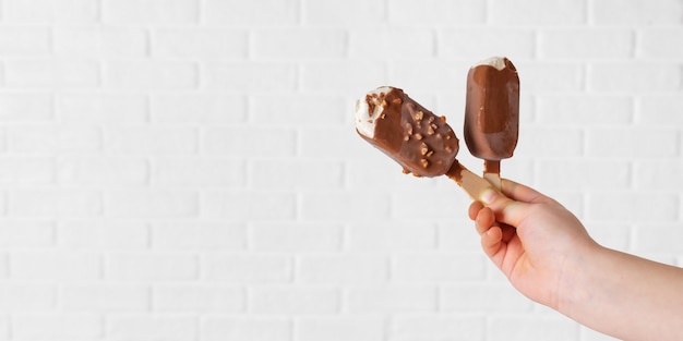 La mano del niño con helado paleta sobre fondo blanco