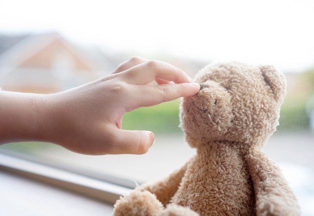 Mano de niño jugando con la nariz de oso de peluche