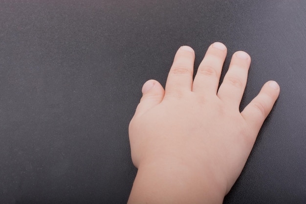 Mano de niño pequeño con fondo de color oscuro