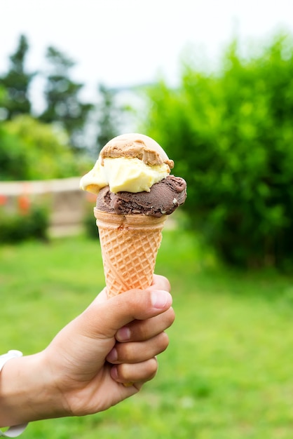 La mano de un niño pequeño sosteniendo un cono de helado que gotea