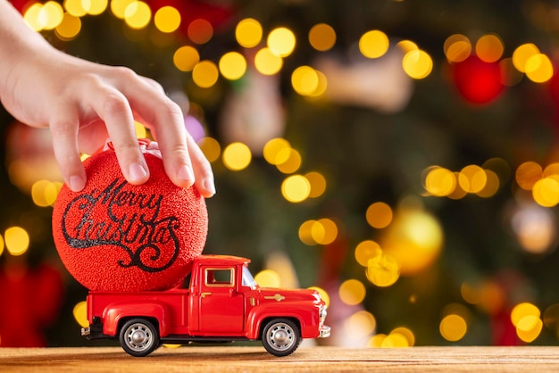 Foto una mano de niño pone una pelota de navidad en la parte trasera de una camioneta retro roja