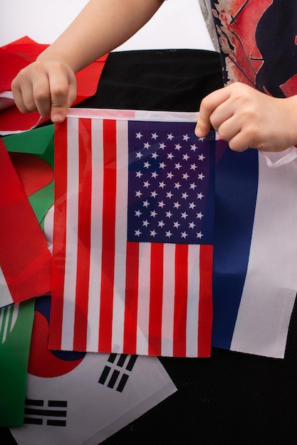 Mano de niño sosteniendo una bandera estadounidense en la mano