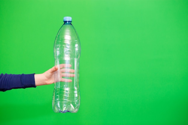 Mano de niño sosteniendo una botella de plástico