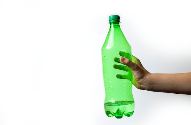 La mano de un niño sostiene una botella verde sobre un fondo blanco.