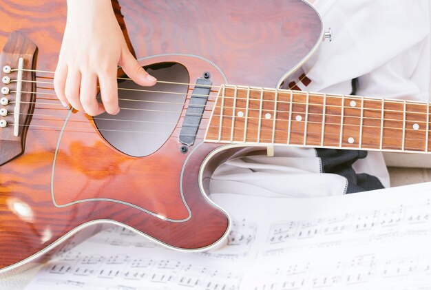 Mano de niño tocando la guitarra acústica.