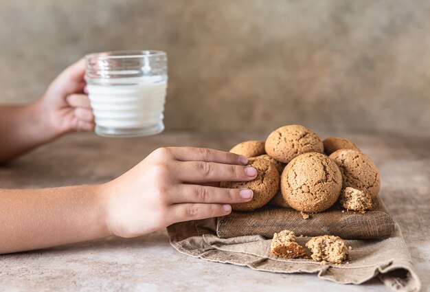 La mano del niño toma las galletas de avena del tablero Merienda o postre saludable