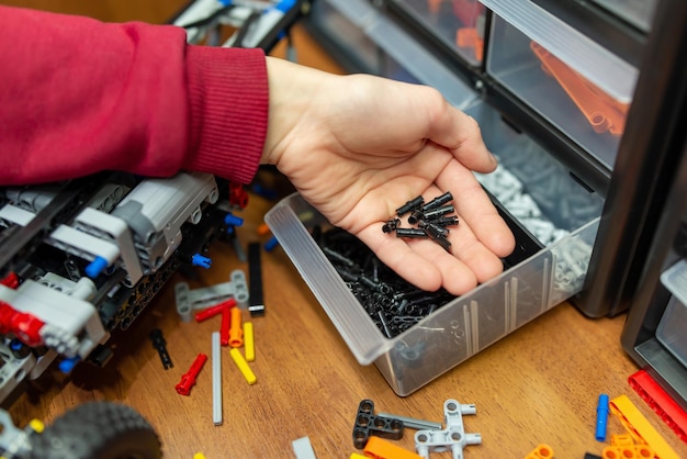 Mano de un niño tomando algunas piezas para construir una máquina robótica Niño jugando con un constructor de ingeniería