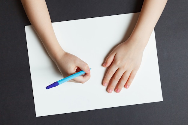 La mano de los niños con un bolígrafo sobre un papel blanco