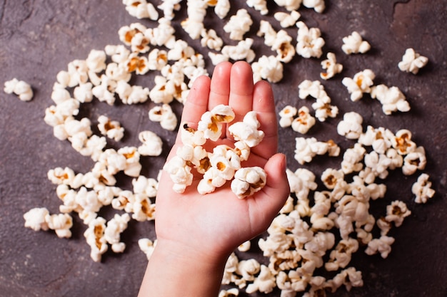 Mano de los niños sosteniendo un montón de palomitas de maíz frescas closeup