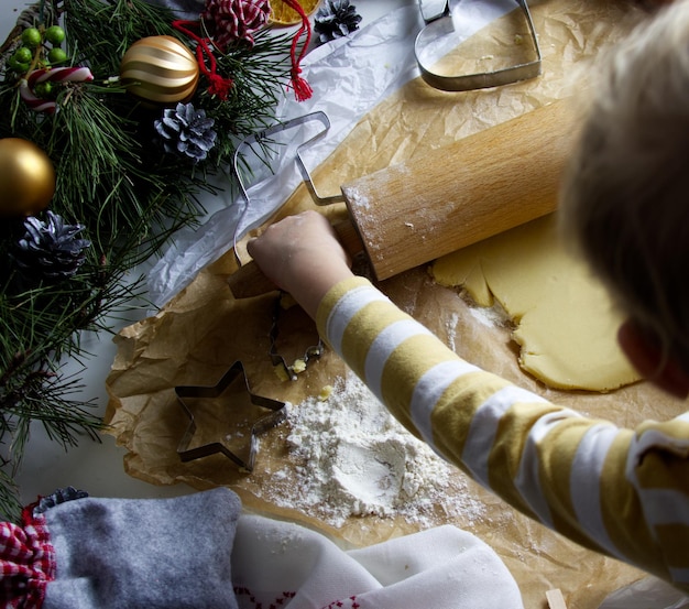 La mano de los niños talla figuritas para galletas navideñas de la masa