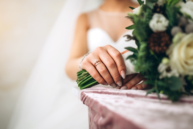 Mano de novia con anillo y flores.