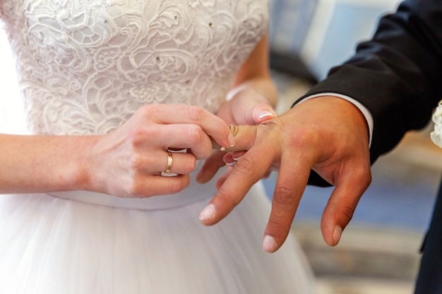 Mano de la novia que pone el anillo de bodas en el dedo del novio