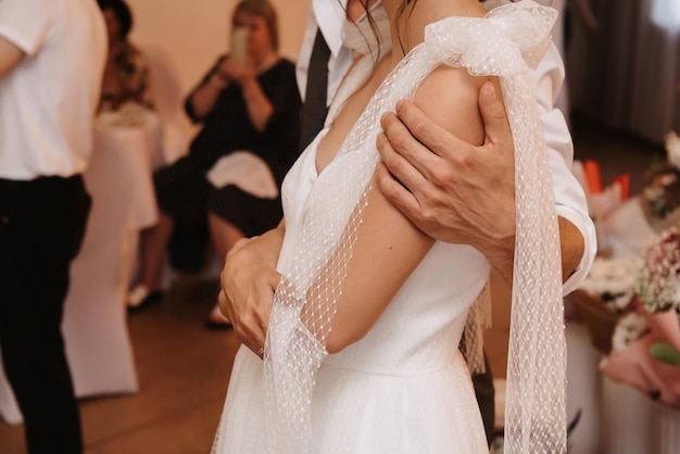 La mano del novio abraza a la novia el día de la boda