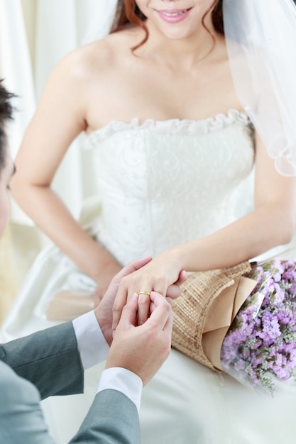 La mano del novio lleva un anillo de bodas para la novia.