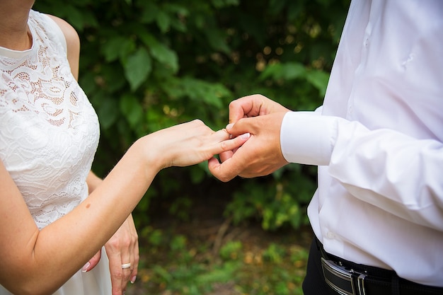 La mano del novio poniendo un anillo de bodas en el dedo de la novia