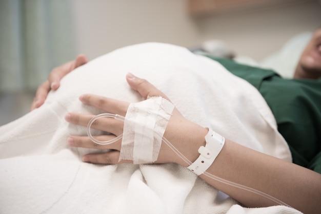 Foto mano de paciente mujer ingresada en el hospital con solución salina intravenosa (iv)