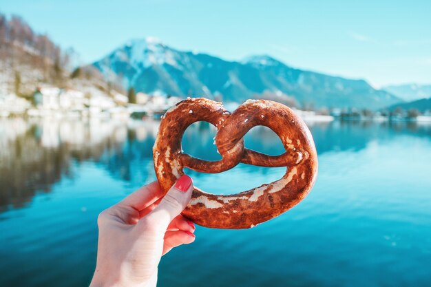 Mano con pan tradicional en el fondo del lago de montaña en los Alpes bávaros, Alemania.