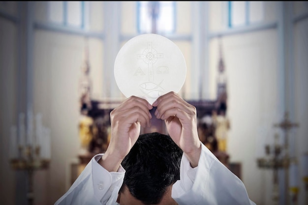 Foto la mano del pastor levanta un pan de comunión en la iglesia