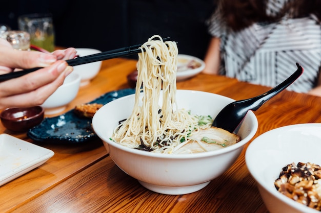 Foto mano pellizcando al estilo hakata shio chashumen (sopa de sal) con palillos.