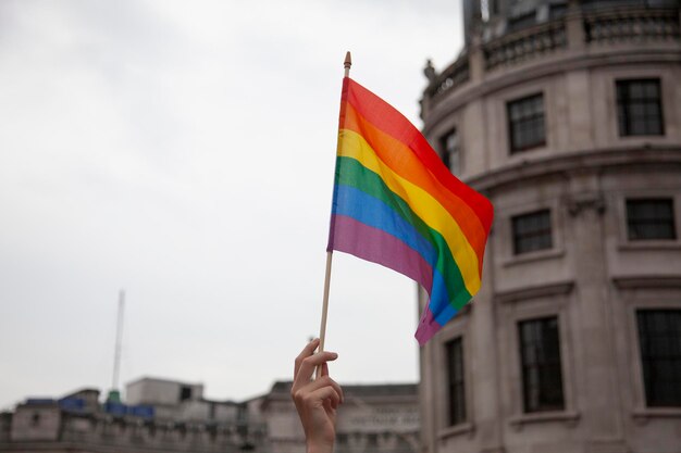 La mano de una persona ondeando una bandera del orgullo gay