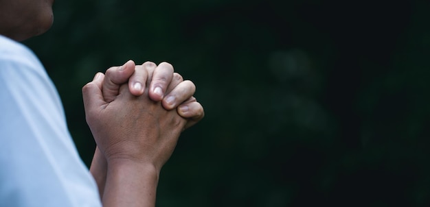 Foto mano de persona de oración en fondo negro la mujer católica cristiana está orando a dios en la oscuridad en la iglesia las niñas creen y tienen fe en jesucristo la religión de cristo y el cristianismo adoran o rezan concepto