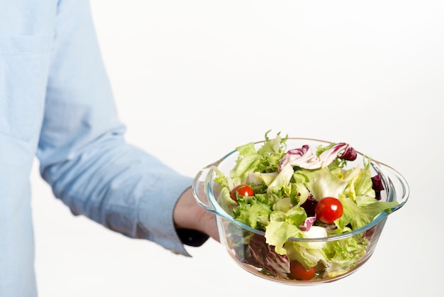 Mano de la persona que muestra un tazón de ensalada saludable