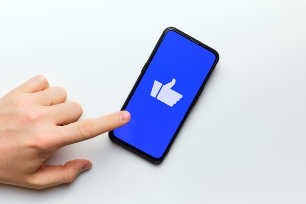 Foto la mano de la persona quiere presionar el pulgar hacia arriba para la evaluación en internet utilizando un teléfono inteligente.