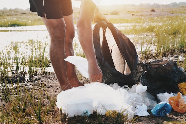 Mano de personas recogiendo basura de plástico para limpiar en el parque del río