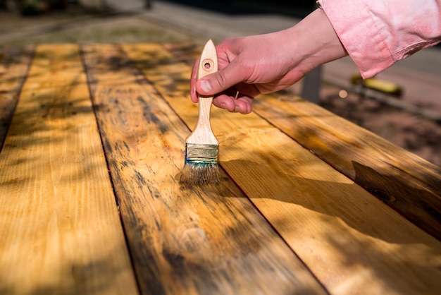 Foto mano con un pincel barniza tablas de madera antiguas