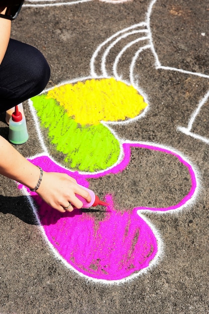 Foto mano pintando arena en el suelo en forma de corazón