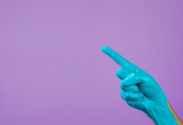 Mano en pintura azul sobre un fondo morado, puntos de dedo para copiar espacio