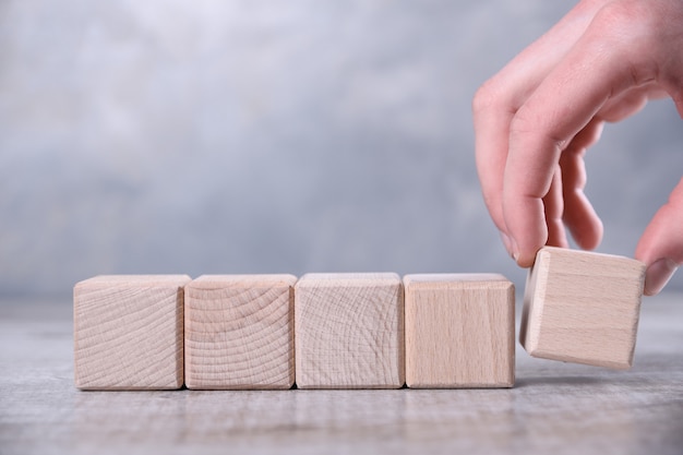 La mano pone el cubo de madera en blanco con espacio para su palabra, letra, símbolo sobre la mesa. Lugar para texto, espacio de copia libre