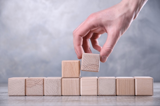 La mano pone un cubo de madera en blanco con espacio para tu palabra